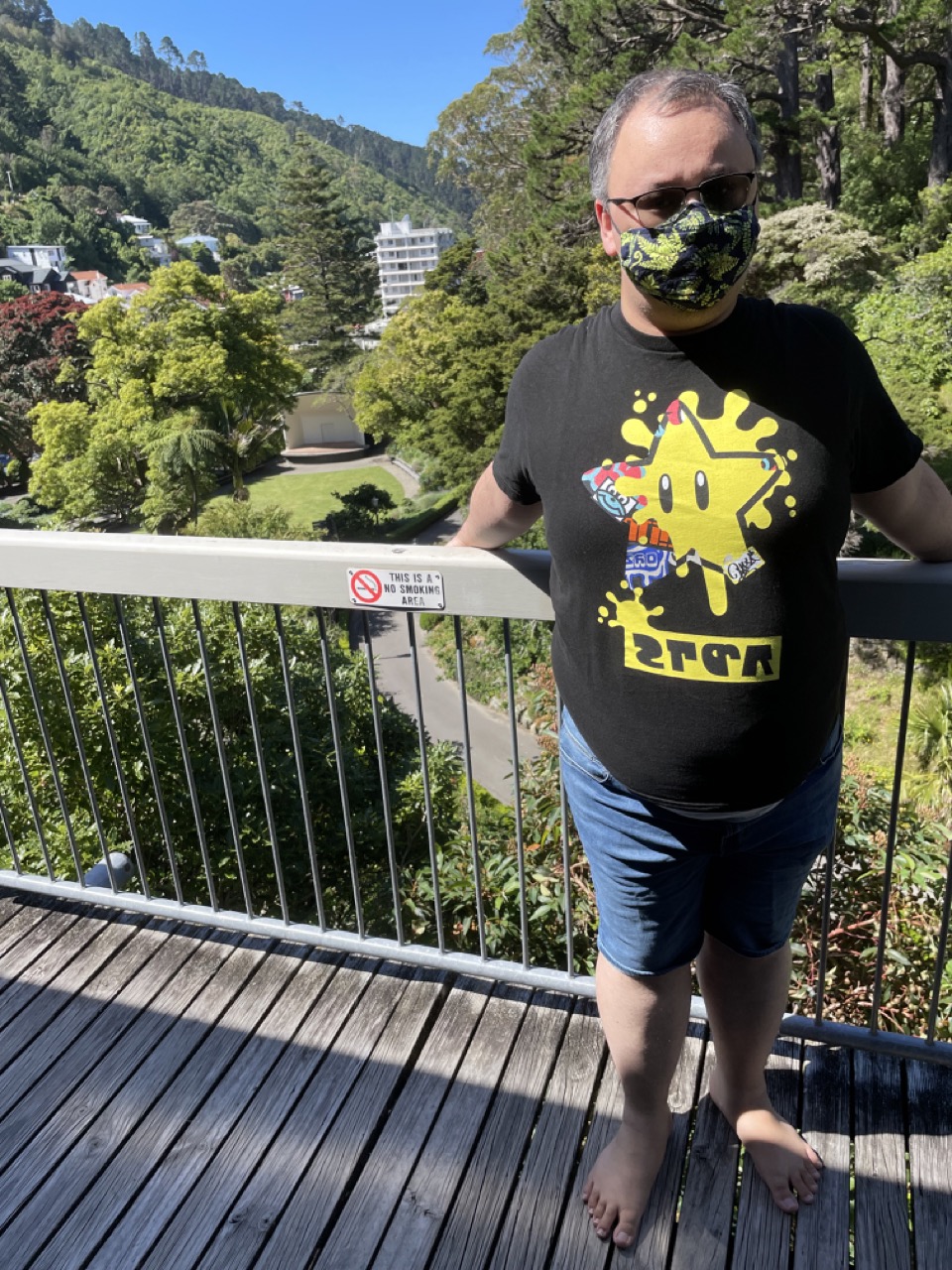 Feets stands on a verrandah overlooking a path and some green trees