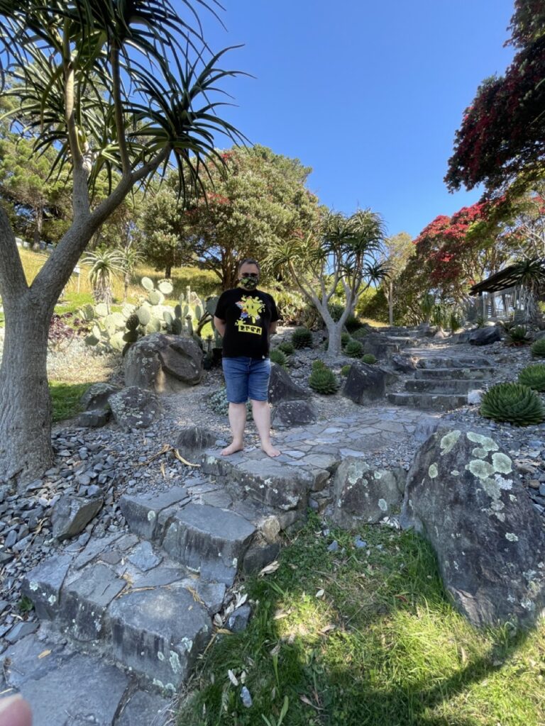 Feets stand on stone steps in the Botanic Gardens, surrounded by greenery and a blue sky