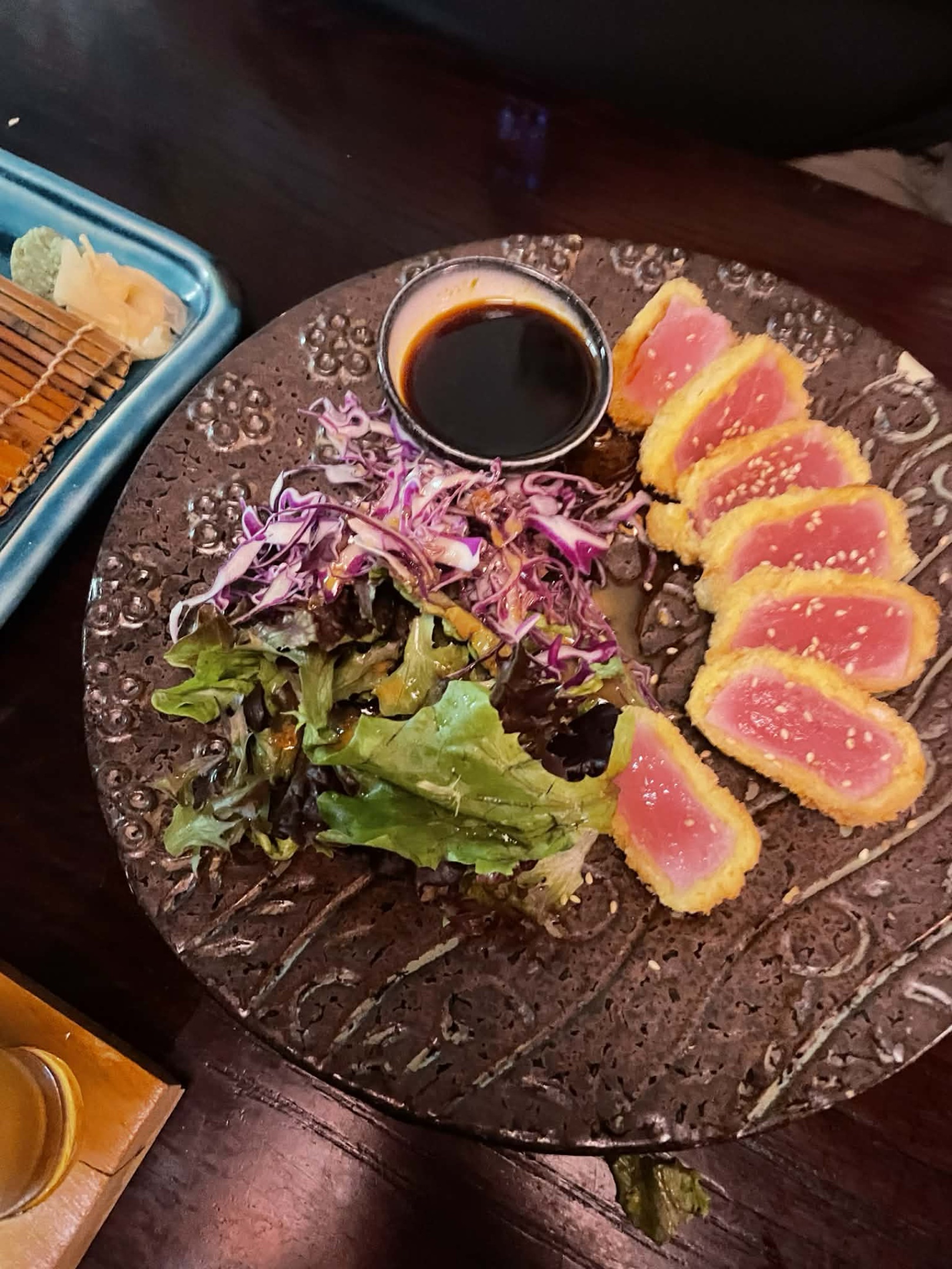 Tuna katsu, small slices of tuna with breadcrumbs on the outside, with a side of lettuce and onions.