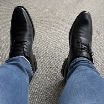 My feet with black shoes at the end of my blue jeans