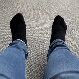 My feet wearing black socks, at the end of my blue jeans